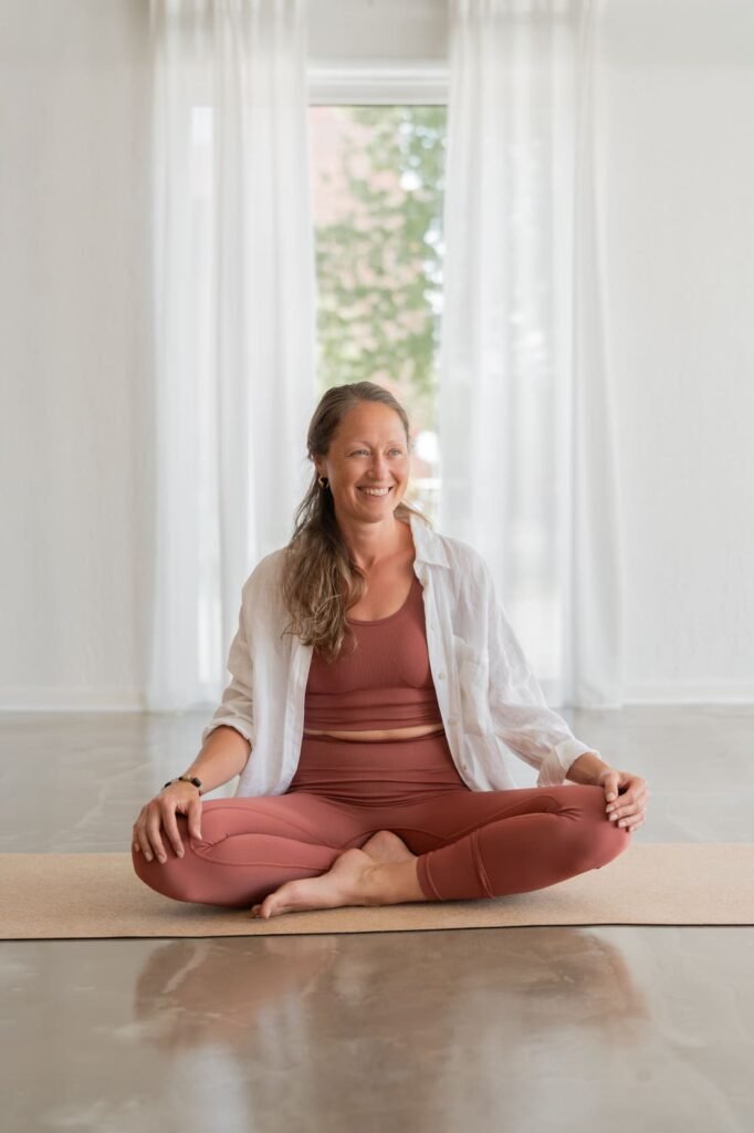 Yogalærer sidder i smilende under undervisning hos IndreRo Yoga i Silkeborg.
